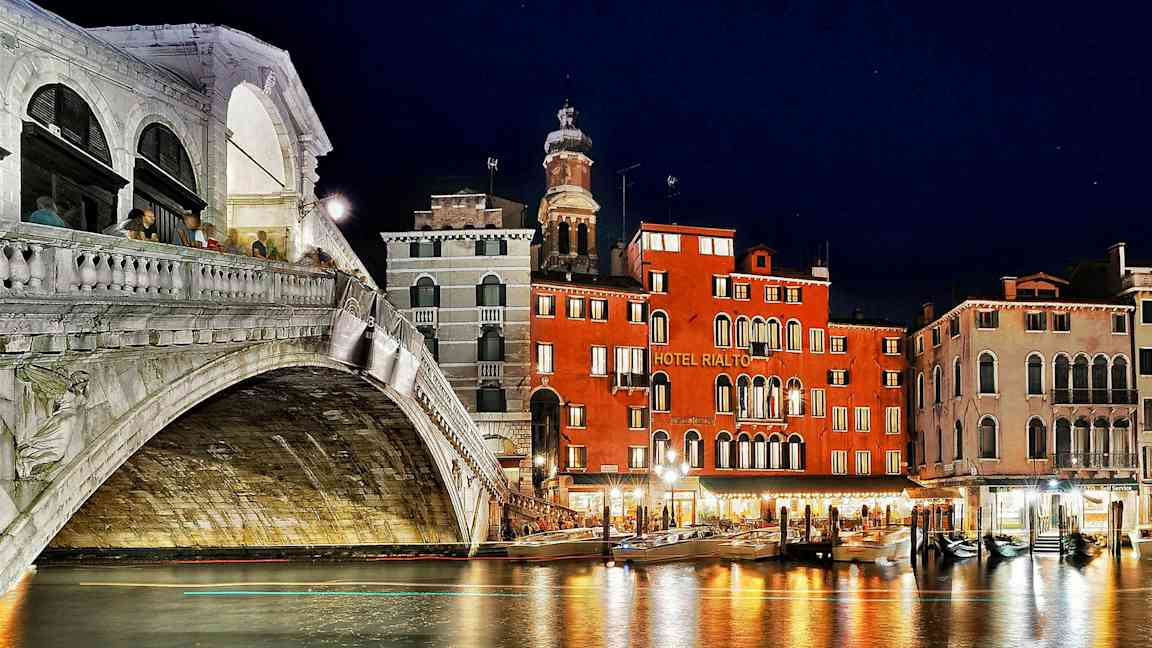 En natudsigt af Rialto-broen og nærliggende bygninger ved Grand Canal i Venedig. (AI-genereret tekst)