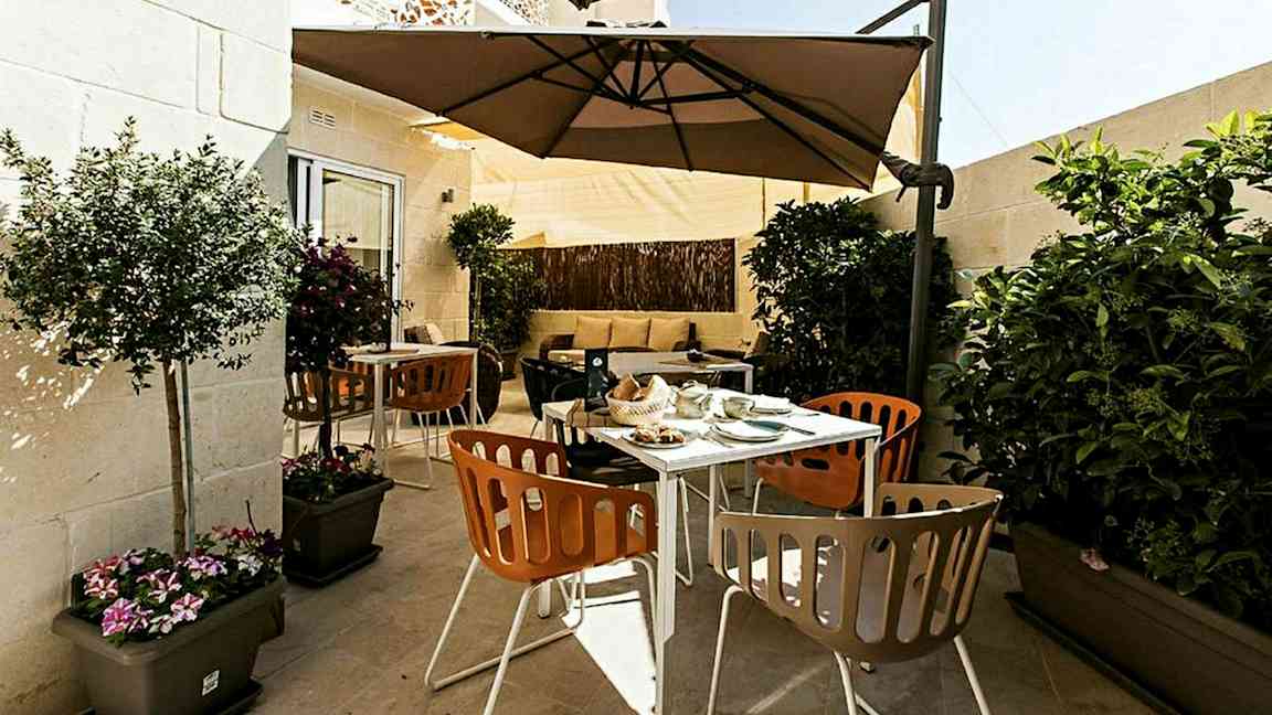 En terrasse med udendørsmøbler, parasoller og planter. (AI-genereret tekst)