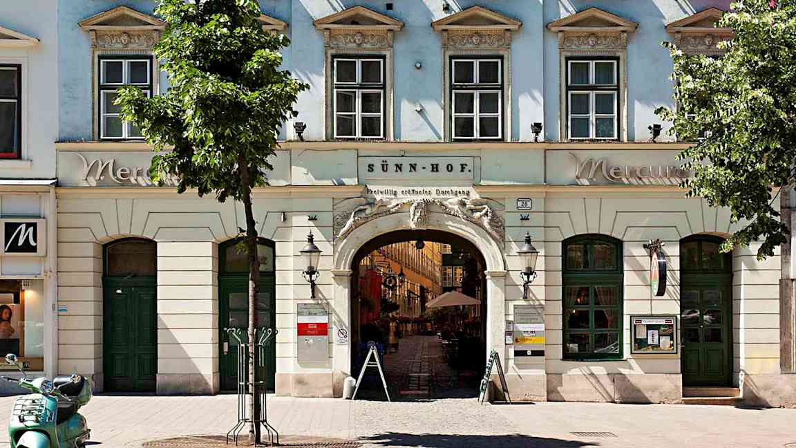 En bygning med vinduer, bueindgang og blomsterkasser ved vinduerne. (AI-genereret tekst)