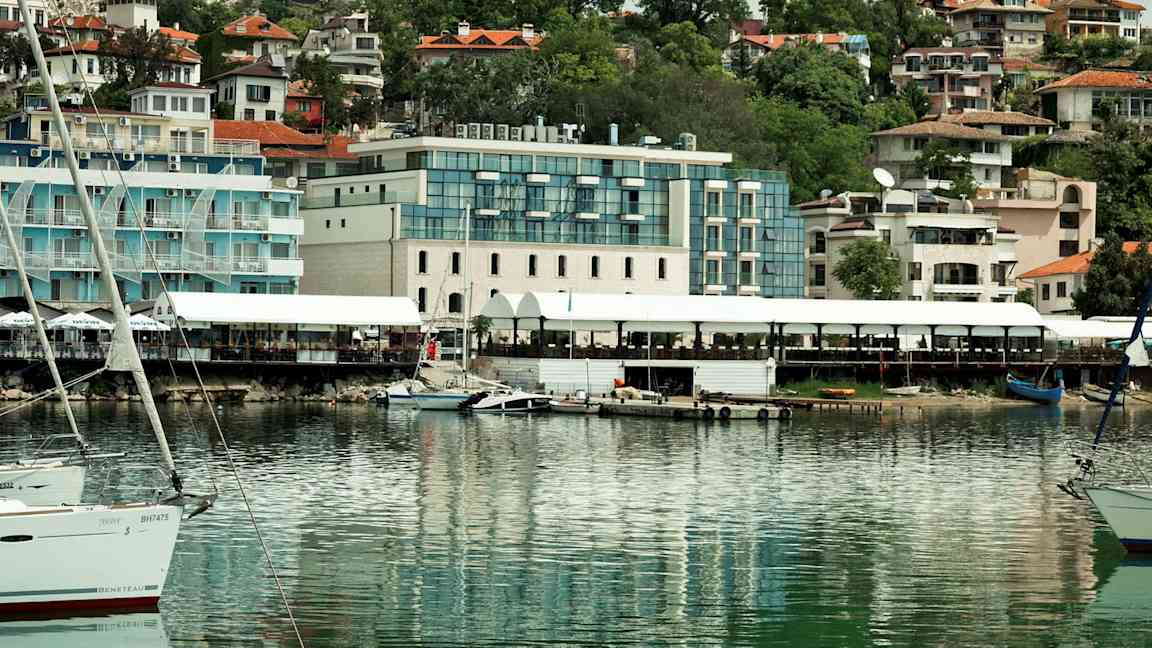 Billede af en havn med både og bygninger i baggrunden. (AI-genereret tekst)