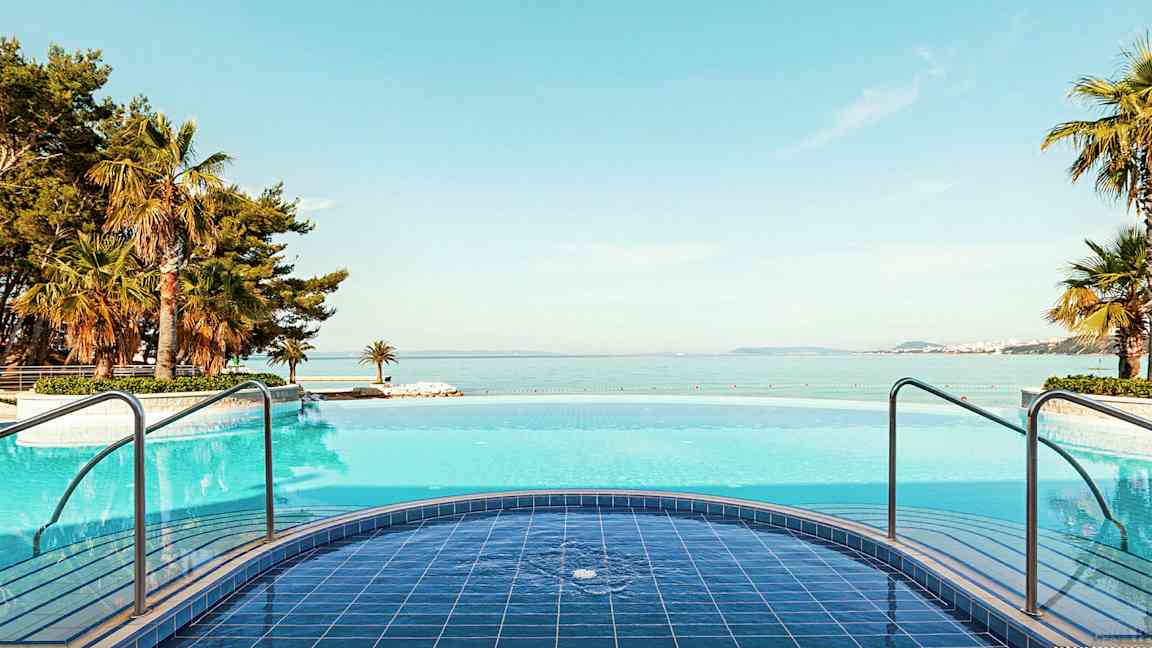 Pool med havudsigt og omkringliggende palmer. (AI-genereret tekst)