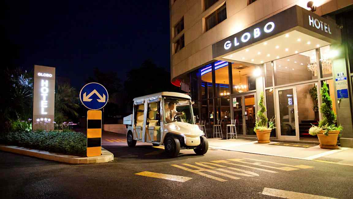 Et hotel set om natten med navnet Globo, en elbil er parkeret foran indgangen. (AI-genereret tekst)