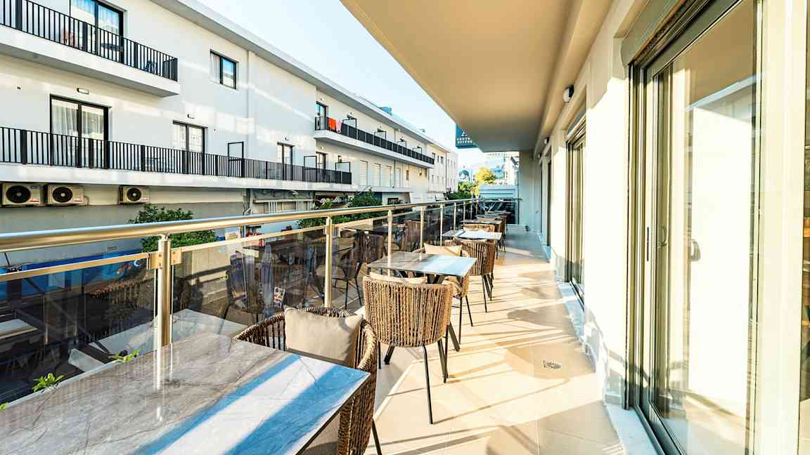 En altan med borde og stole samt udsigt til nabobygninger. (AI-genereret tekst)