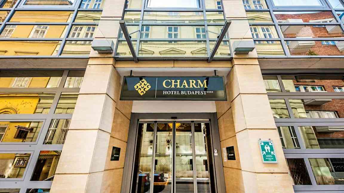 Indgangen til et hotel med skiltet "Charm Hotel Budapest". (AI-genereret tekst)