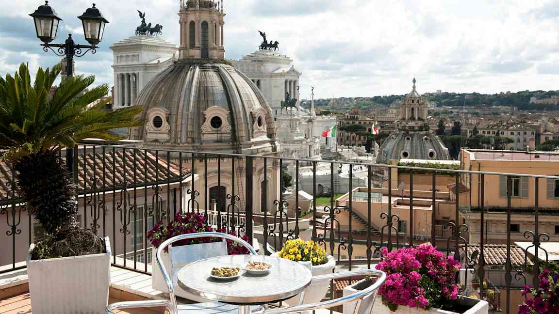 Billede af en terrasse med udsigt over Roms arkitektur, herunder kupler og monumenter. (AI-genereret tekst)