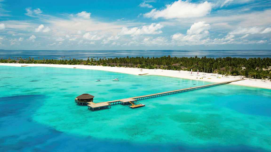 Luftfoto af en tropisk strand med en mole, der strækker sig ud i det turkise vand. (AI-genereret tekst)