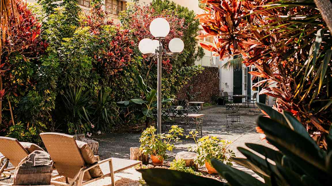 En solrig gårdsplads med havemøbler og beplantning. (AI-genereret tekst)