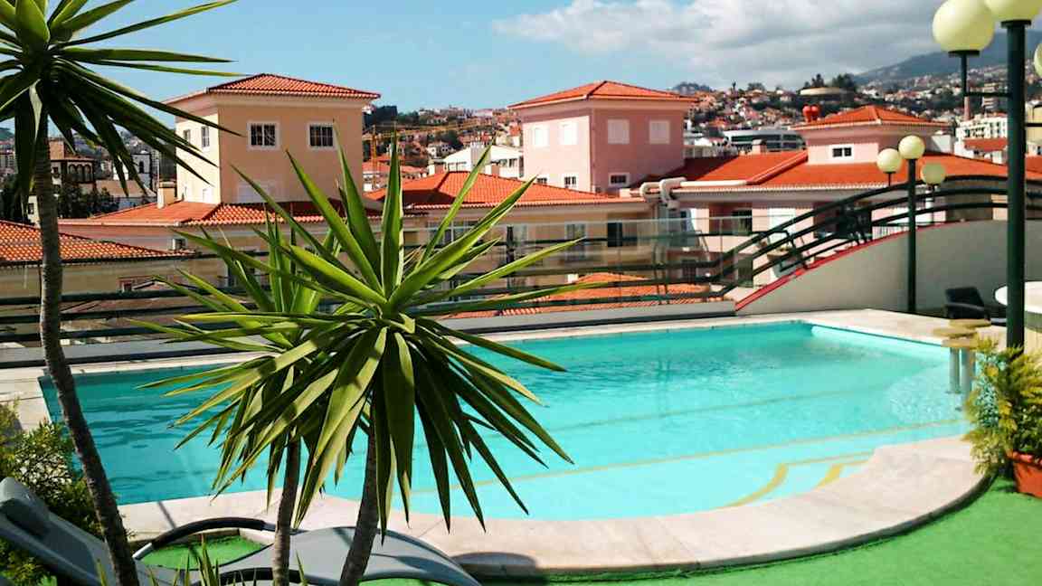 En pool omgivet af grønne områder og en baggrund med huse med røde tegltage. (AI-genereret tekst)