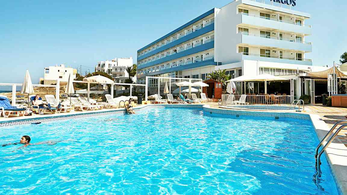 Et hotel med en udendørs pool og omgivelser med liggestole og parasoller. (AI-genereret tekst)