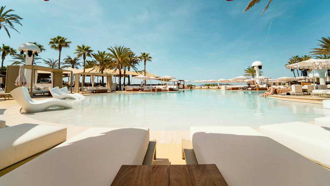 En luksuriøs pool omgivet af solsenge og parasoller i en sommerlig atmosfære. (AI-genereret tekst)