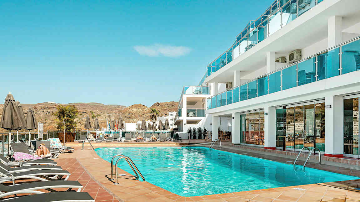 Poolområde ved hotel med liggestole og parasoller. (AI-genereret tekst)