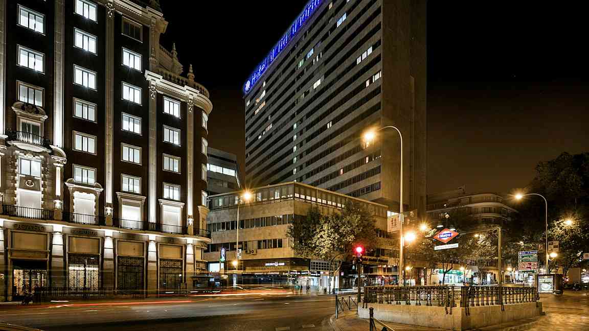 En byvej om natten med oplyste bygninger og lysskilte. (AI-genereret tekst)