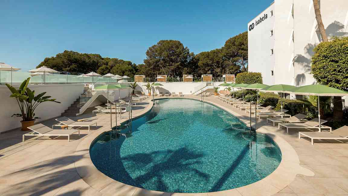 Billedet viser en udendørs pool omgivet af liggestole og parasoller, med vegetation i baggrunden og en hotelbygning til højre. (AI-genereret tekst)