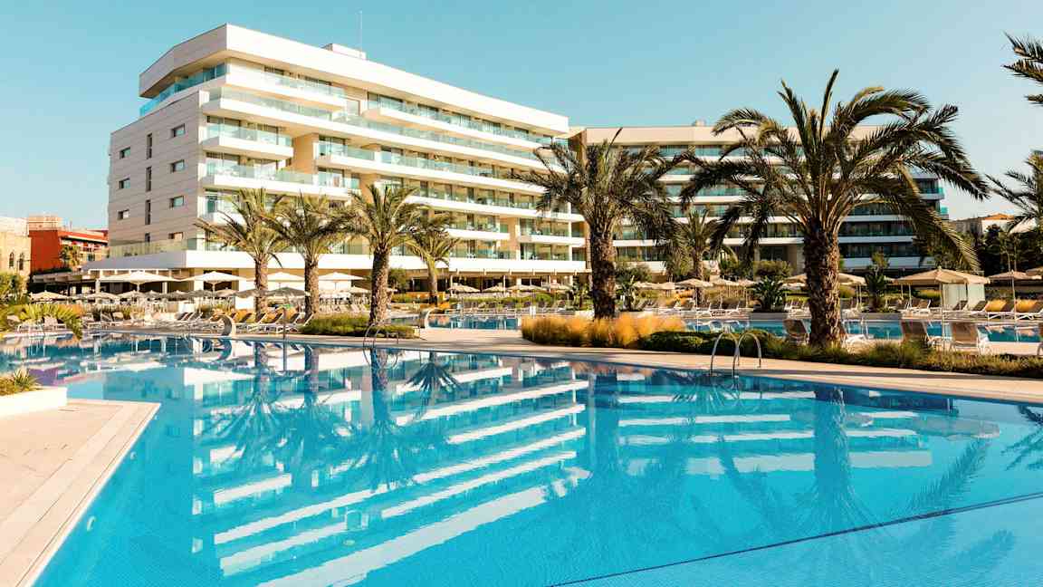 Hotel med pool og palmer i et solrigt område. (AI-genereret tekst)