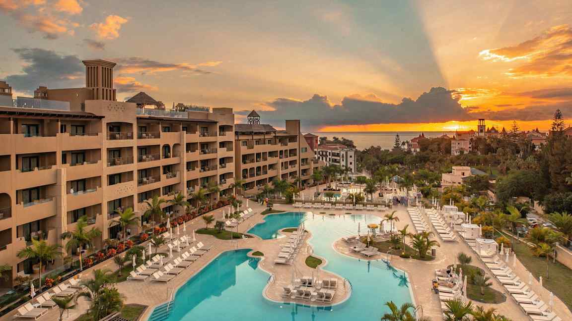 Udsigt over et hotel med poolområde ved solnedgang. (AI-genereret tekst)