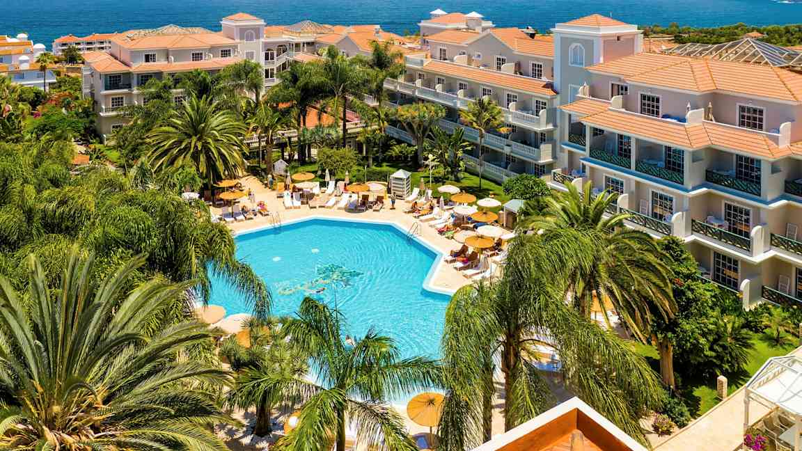 Hotel med poolområde og omkringliggende grønne områder ved kysten. (AI-genereret tekst)