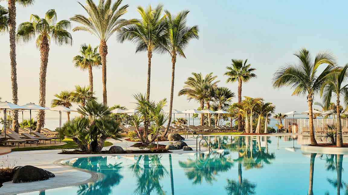 Poolområde med klart blåt vand og palmer. (AI-genereret tekst)