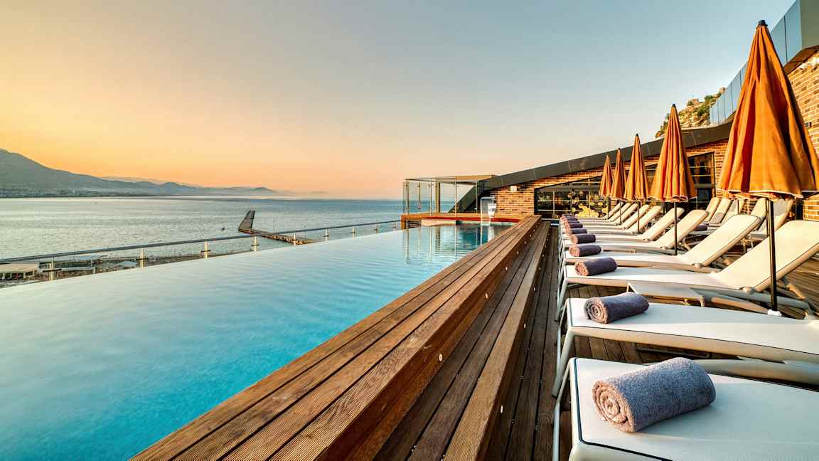 Strandområde med swimmingpool, liggestole og orange parasoller. (AI-genereret tekst)