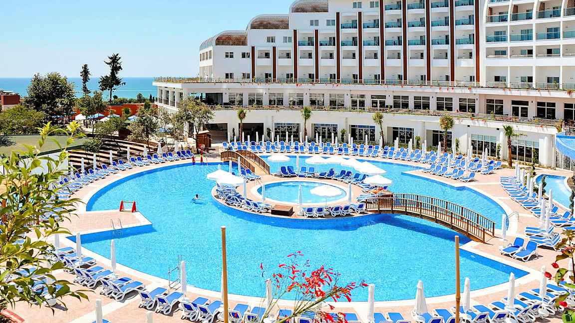 Hotel med stor pool og liggestole ved havet. (AI-genereret tekst)