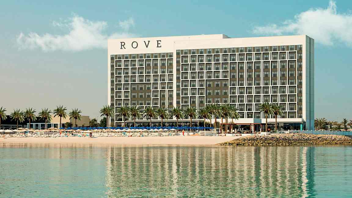 Et hotel ved en strand med palmer. (AI-genereret tekst)