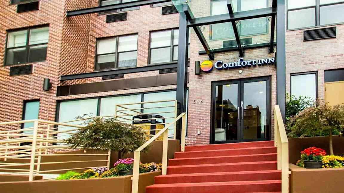 Indgangen til en bygning med teksten "Comfort Inn" over døren. (AI-genereret tekst)