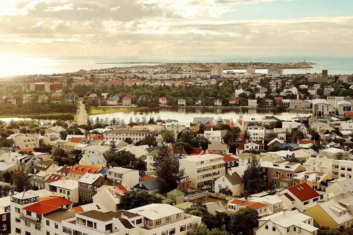 Udsigt over en by med mange farverige huse, en flod og en kystlinje i baggrunden. (AI-genereret tekst)