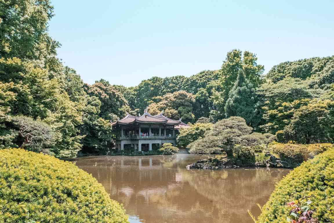 En kinesisk pavillon ved en dam i en frodig park. (AI-genereret tekst)