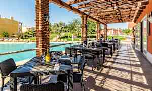 Udendørs servering med borde og stole ved en pool. (AI-genereret tekst)