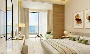 Et moderne hotelværelse med havudsigt, møbleret med en stor seng, en grøn sofa og en altan. (AI-genereret tekst)