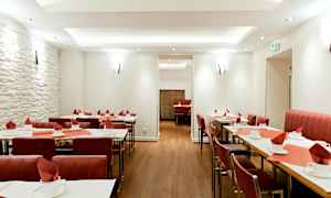 Restaurant med dækkede borde og røde stole. (AI-genereret tekst)