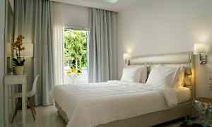 Lyst og moderne indrettet hotelværelse med en stor seng og vindue med udsigt. (AI-genereret tekst)