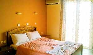 Et soveværelse med en dobbeltseng, orange sengetøj og to håndklæder dekoreret på sengen. (AI-genereret tekst)