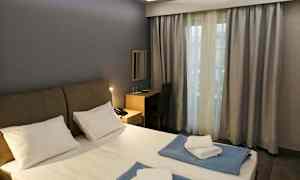 Et hotelværelse med en dobbeltseng, skrivebord og et vindue med gardiner. (AI-genereret tekst)