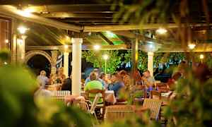 Udendørs servering med mennesker, der sidder ved borde under et tag. (AI-genereret tekst)