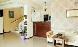 Lyst hotelreceptionsområde med sofa, træbord og marmoreret trappe. (AI-genereret tekst)