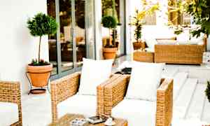 Havemøbler med flet og hvide puder på en terrasse. (AI-genereret tekst)