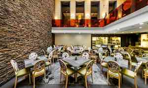 Interiør af en restaurant med stole og borde samt en væg af sten. (AI-genereret tekst)