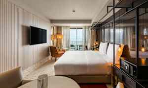 Hotelværelse med dobbeltseng, siddepladser og TV samt balkon med udsigt. (AI-genereret tekst)