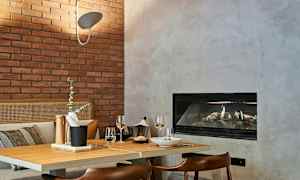 En hyggelig spiseplads med et bord af træ, en bakke med tilbehør, to vinglas og pejs i baggrunden. (AI-genereret tekst)