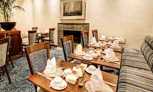 Et pænt opdækket rum med træstole og opredte borde. (AI-genereret tekst)