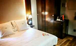 Et hotelværelse med en seng og en oplyst natlampe ved siden af et mørkt træskab. (AI-genereret tekst)