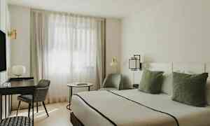 Et moderne indrettet værelse med en seng, skrivebord, stol og vindue med tynde gardiner. (AI-genereret tekst)