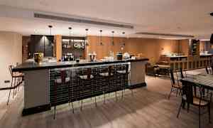 En moderne bar med høje stole omkring en bardisk og et veludformet interiør. (AI-genereret tekst)