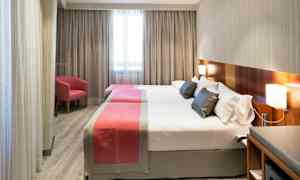 Hotelværelse med to separate senge, enkelte moderne møbler og et vindue i baggrunden. (AI-genereret tekst)