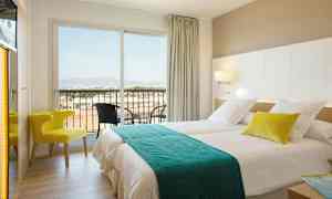 Et hotelværelse med to senge, en stol og en altan med udsigt. (AI-genereret tekst)