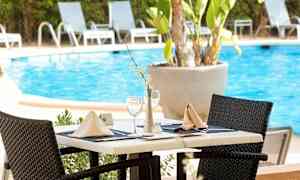 Et dækket bord ved en pool omgivet af liggestole. (AI-genereret tekst)