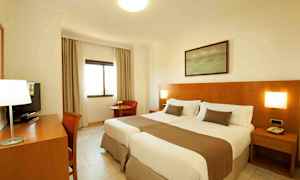 Et hotelværelse med to enkeltsenge og træpanel på væggen. (AI-genereret tekst)