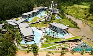 Luftfotografi af et hotelområde med pools og omkringliggende grønne områder. (AI-genereret tekst)