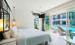 Hotelværelse med redt seng og udsigt over en pool udenfor. (AI-genereret tekst)