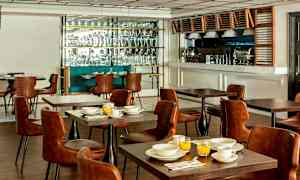 Restaurant med bord og stole samt buffetområde. (AI-genereret tekst)